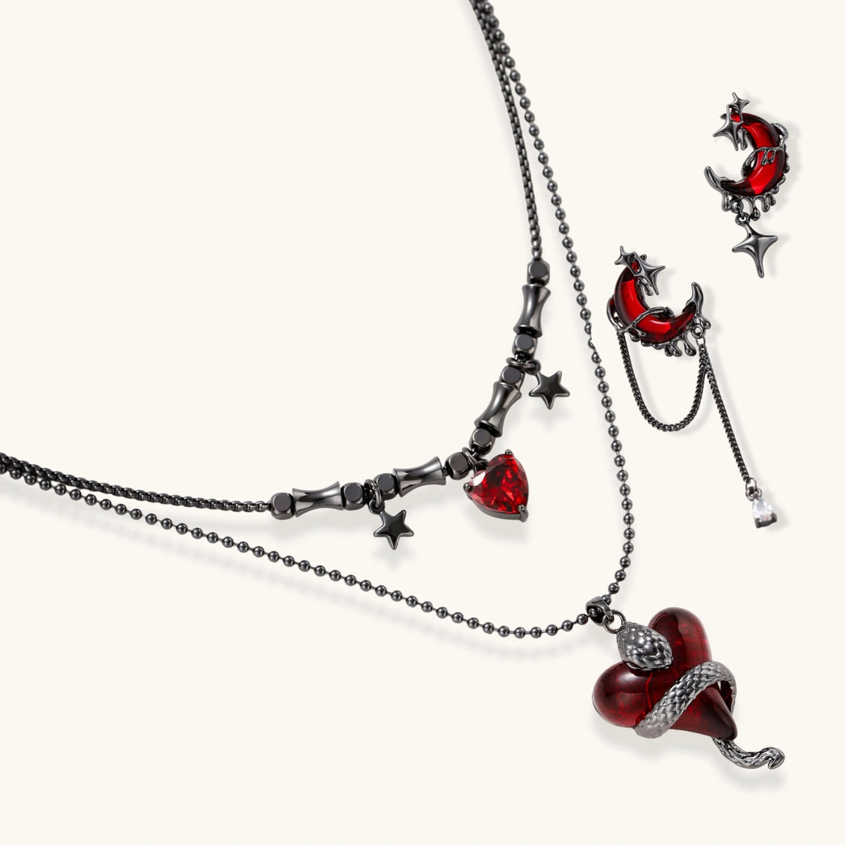 Gothic jewelry set with asymmetrical black metal earrings featuring red crescent moons, stars, and layered necklaces with heart pendants